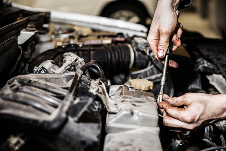 Automobile service worker or garage mechanic hand holding vehicle motor maintenance tool repairing auto car engineの写真素材