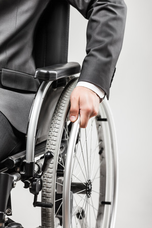 Business career and professional competition success concept - invalid or disabled businessman in black suit sitting wheelchair white isolatedの写真素材