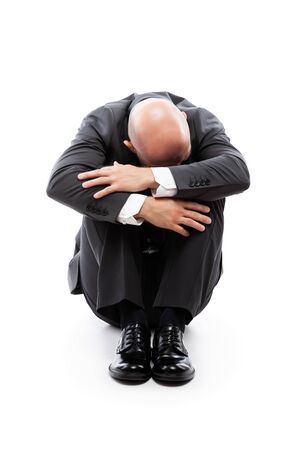 Business problems and failure at work concept - unhappy crying tired or stressed businessman sitting in depression hand hiding face white isolatedの写真素材