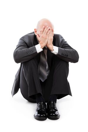 Business problems and failure at work concept - unhappy crying tired or stressed businessman sitting in depression hand hiding face white isolatedの写真素材