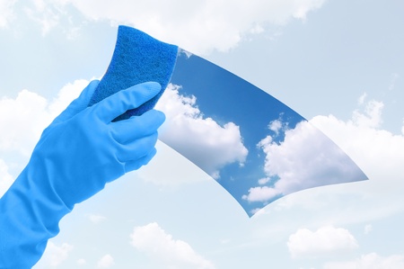 Hand in gloves cleaning the window with blue sponge の写真素材