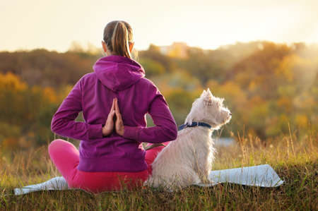 Woman sitting practicing yoga pose against sundownの写真素材