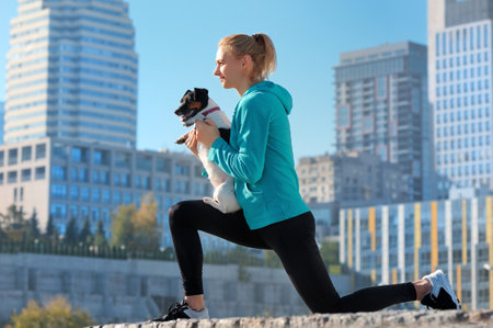Woman making lunge exercise holding dog in handsの写真素材