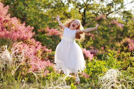 Pretty girl jumping of happiness at the blooming parkの写真素材