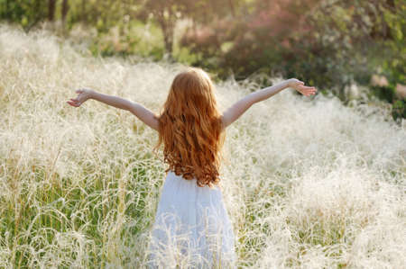 Girl with spread hands of happiness view from backの写真素材