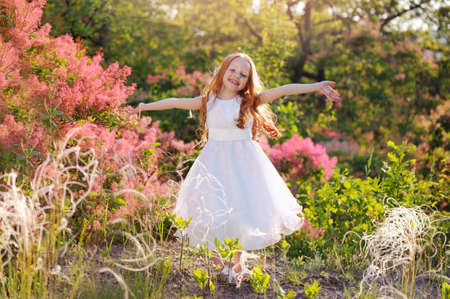 Girl with spread hands in the park of blooming bushesの写真素材
