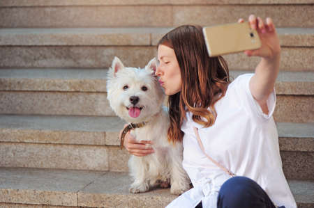 Woman making selfie picture of her kissing the dogの写真素材