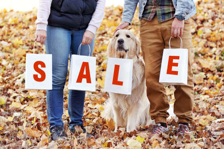 Family with a dog holding paper bags with SALE on themの写真素材