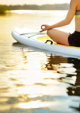 Closeup picture of mudra fingers gesture of woman meditating on paddle boardの写真素材