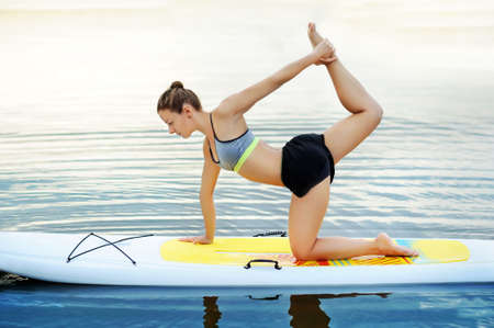 Woman practicing yoga on paddle board