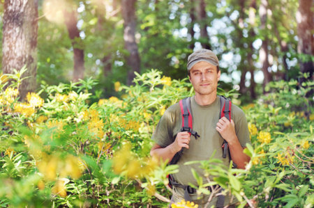Portrait of a positive young man at his journey through the forest