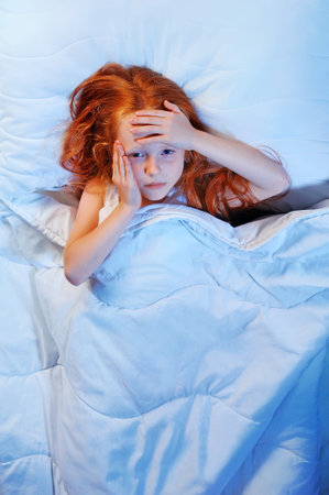 Depressed girl in bed having headacheの写真素材