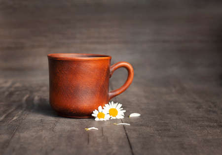 earthenware mug with chamomile flowers close-up on a black backgroundの写真素材