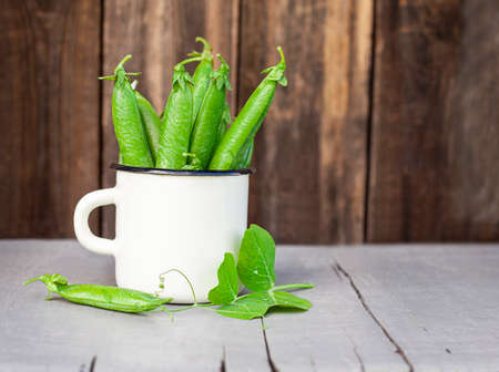 mug with pods of green peas on a gray tableの写真素材