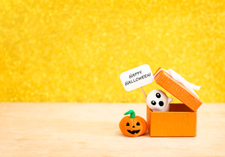 gift box with ghost and pumpkin on wooden table on bokeh backgroundの写真素材