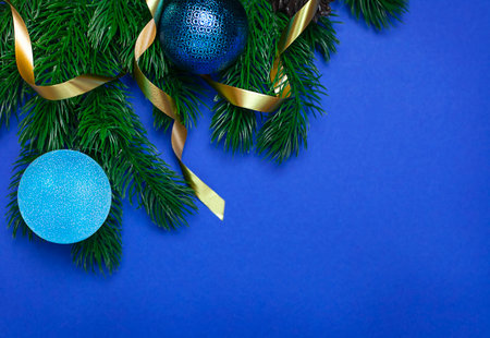 Christmas tree branch with blue balls on an empty blue backgroundの写真素材