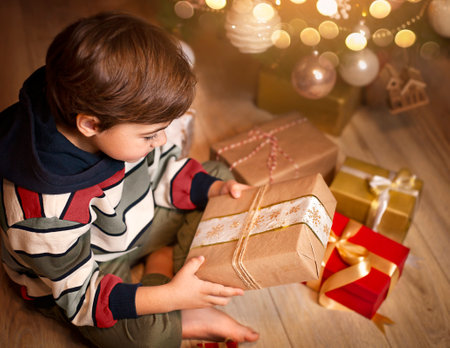 a small child examines gifts under the christmas treeの写真素材