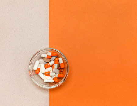 glass cup with medical capsules on an orange background. View from aboveの写真素材