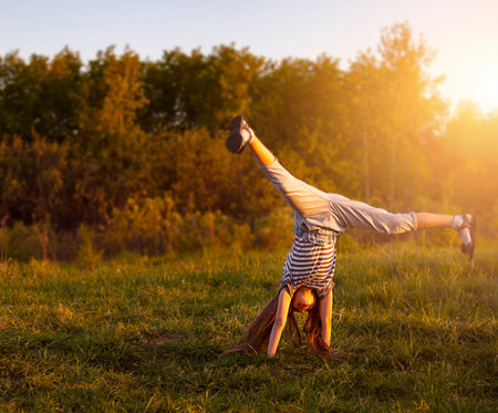 the child is engaged in acrobatics in the meadow at sunset. The concept of a healthy lifestyle.