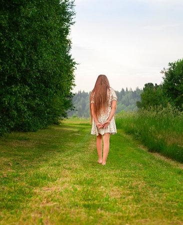 A young girl walks on a green meadow in the summer.の写真素材