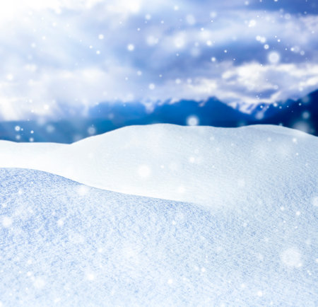 Winter background with snowdrift and blue mountains with snowflakesの写真素材