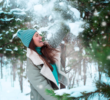 Portrait of a beautiful young woman in the winter forest with snowの写真素材