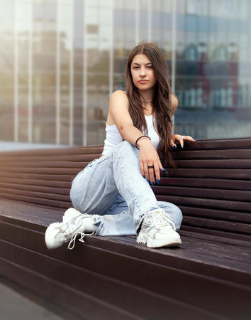 Beautiful young woman sitting on the bench in the city. Outdoor portraitの写真素材