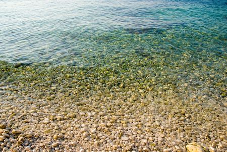yellow pebble and clean ocean waterの写真素材