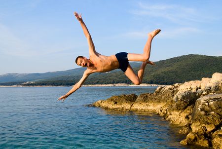 man jumping from rock in sea water and screaming aaaaの写真素材