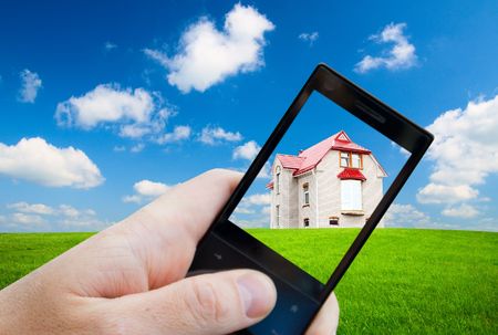 cell phone in hand and houseの写真素材