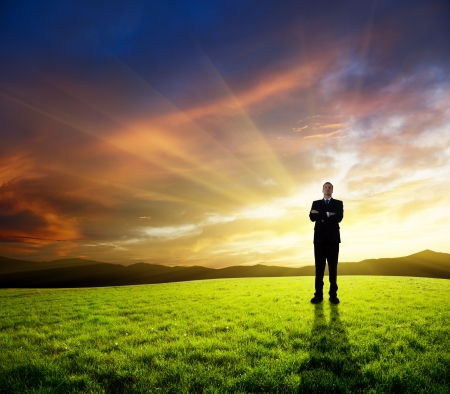 young businessman on green field and sunsetの写真素材