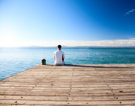 young man relax siting on pierの写真素材