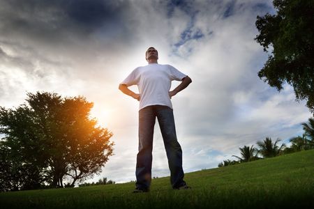 young man relax on green field in sunset timeの写真素材