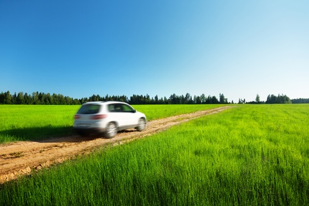 spring field and blured car on ground roadの写真素材