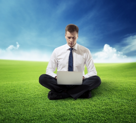 business man with notebook sitting on grassの写真素材