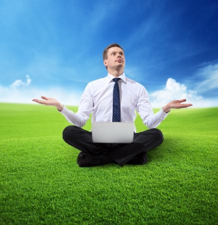 business man with notebook sitting on grassの写真素材