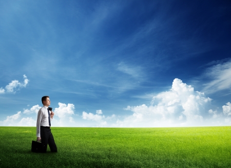 young business man wolking at the field of grassの写真素材
