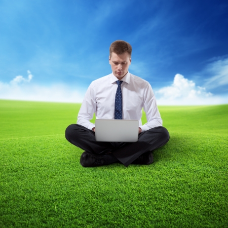 business man with notebook sitting on grassの写真素材