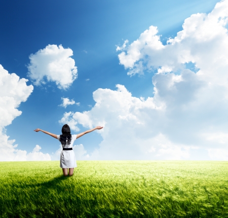 happy young woman in white dress standing at field