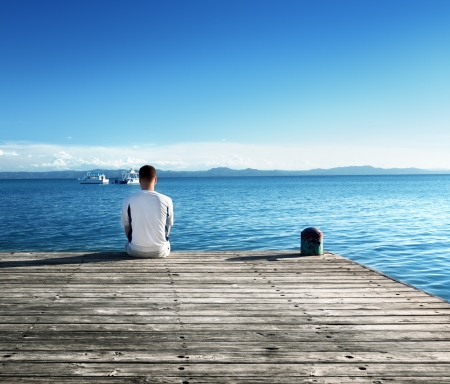 young man relax siting on pier の写真素材