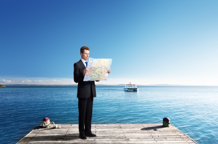 Business man standing on pier with map in handsの写真素材