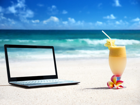 notebook on the beach and glass of fresh jucieの写真素材