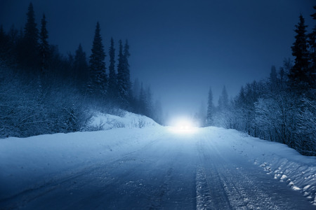 lights of car and winter road in forestの写真素材