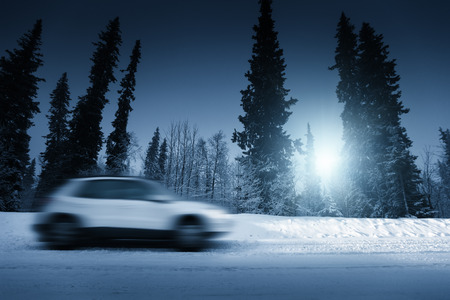 lights of car and winter road in forestの写真素材
