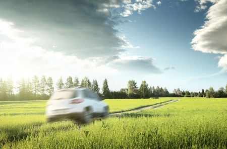 spring field and blured car on ground roadの写真素材