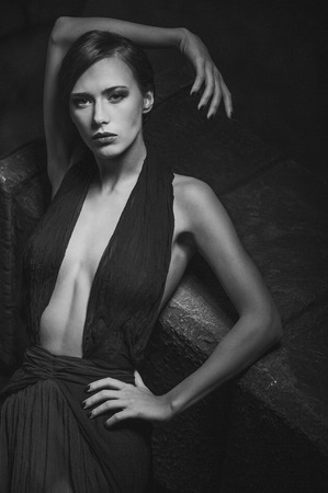 sexy elegant woman dressed in an evening dress. Stone on the background. monochrome imageの写真素材