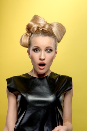 portrait of a young attractive blonde ,  looking with surprise on you. isolated on the yellow backgroundの写真素材