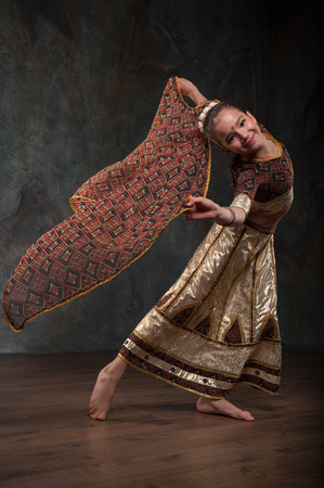 schoolgirl learns Indian dance. Sitting on a stone and repeats the motion, dressed in traditional costumeの写真素材
