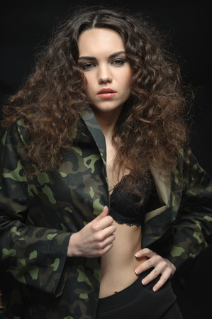 young girl in camouflage slightly bared his body. grey stones in the backgroundの写真素材