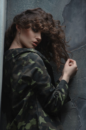 woman in the clothes of a soldier, hiding behind hair. Holds a lock of his hairの写真素材